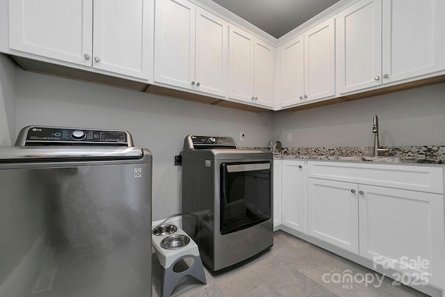 washroom featuring cabinets, washing machine and clothes dryer, and sink