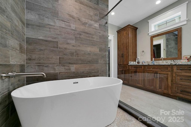 bathroom with vanity, tile patterned flooring, tile walls, and a washtub