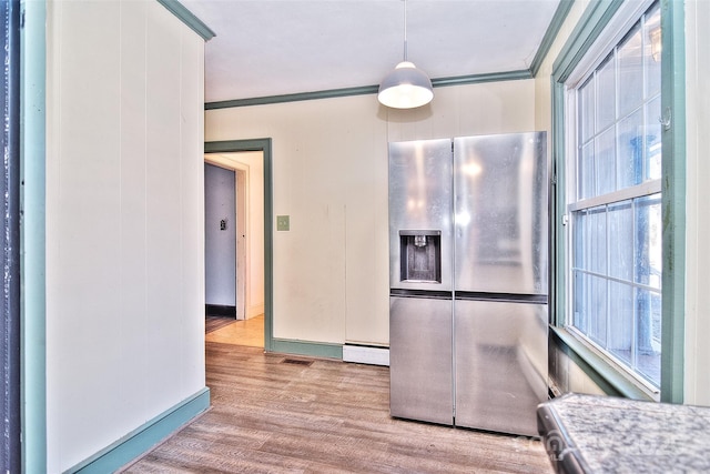 kitchen with stainless steel refrigerator with ice dispenser, ornamental molding, a healthy amount of sunlight, and hanging light fixtures