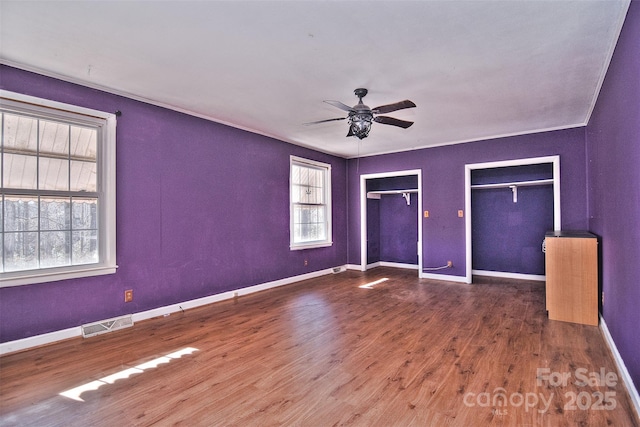 unfurnished bedroom featuring hardwood / wood-style flooring, ceiling fan, and multiple windows