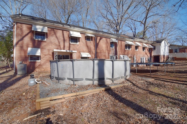 rear view of house with central air condition unit and a trampoline