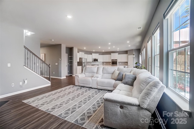 living room with dark wood-type flooring and a healthy amount of sunlight