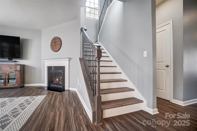 staircase with a towering ceiling and hardwood / wood-style floors