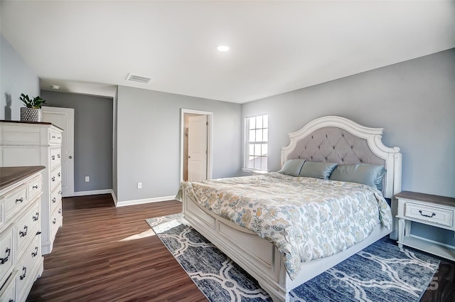 bedroom with ensuite bathroom and dark wood-type flooring