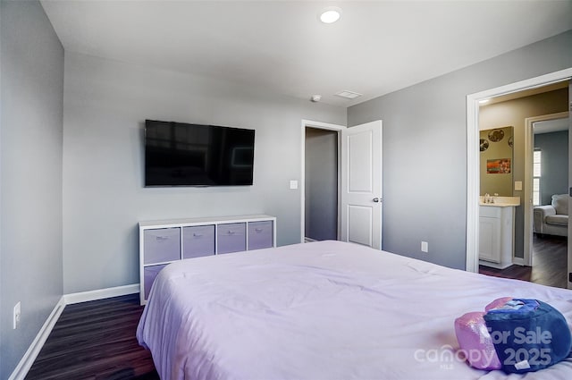 bedroom with ensuite bath and dark hardwood / wood-style floors