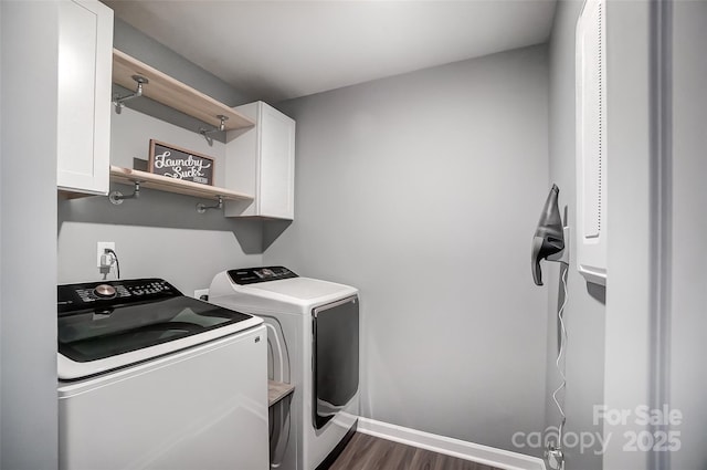 laundry area featuring cabinets, washing machine and clothes dryer, and dark hardwood / wood-style flooring