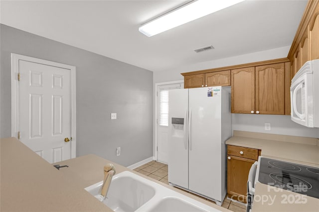 kitchen featuring sink, light tile patterned floors, and white appliances