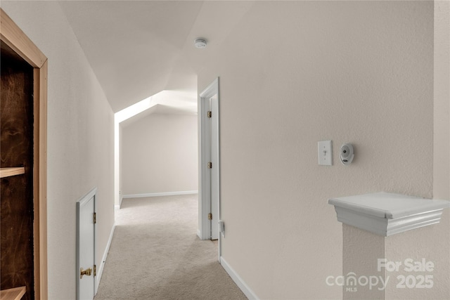 hallway featuring light colored carpet and vaulted ceiling