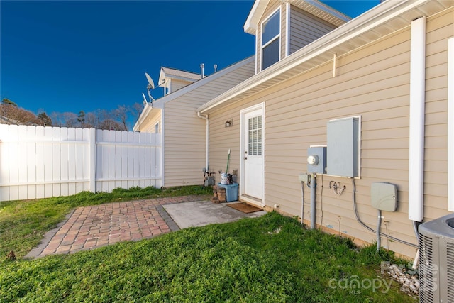 exterior space with cooling unit, a patio area, and a lawn