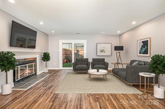 living room with a tile fireplace and hardwood / wood-style flooring