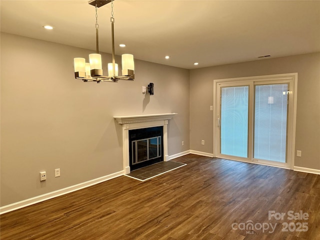 unfurnished living room featuring dark hardwood / wood-style flooring, a wealth of natural light, and a notable chandelier