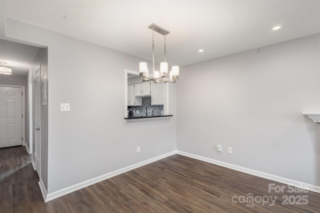 unfurnished dining area with dark wood-type flooring and an inviting chandelier