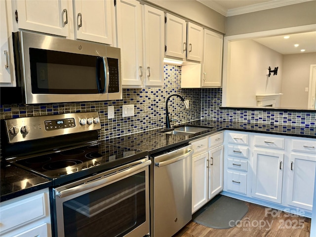 kitchen with white cabinetry, stainless steel appliances, backsplash, crown molding, and sink