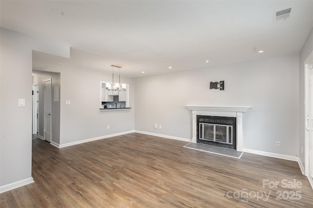 unfurnished living room with an inviting chandelier, dark hardwood / wood-style flooring, and a tile fireplace