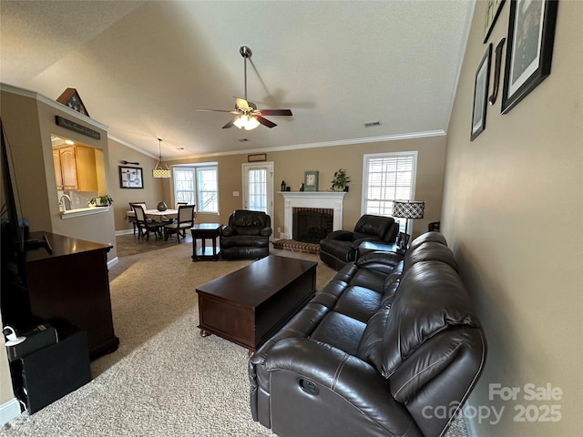 carpeted living room featuring a brick fireplace, vaulted ceiling, ceiling fan, and a healthy amount of sunlight