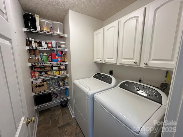 clothes washing area featuring cabinets, a textured ceiling, and washer and clothes dryer