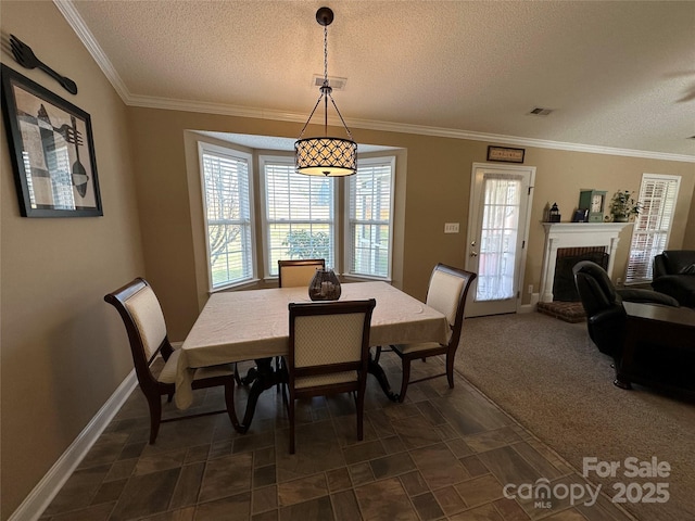 carpeted dining area featuring a fireplace, a textured ceiling, and crown molding