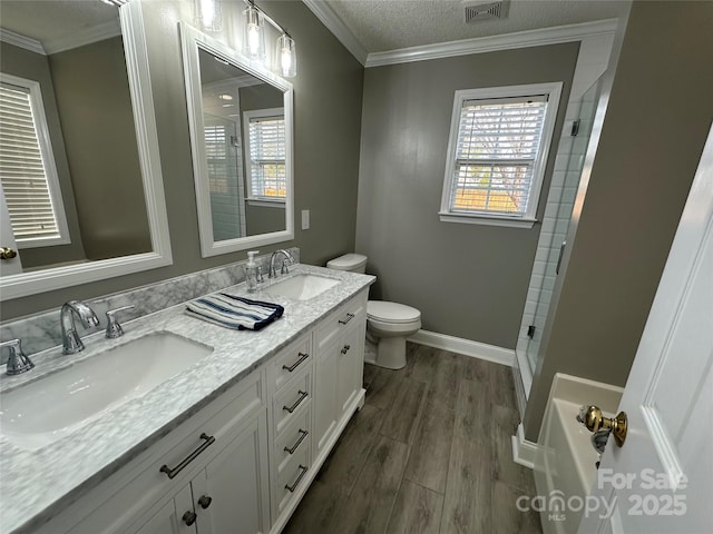 full bathroom featuring vanity, a textured ceiling, crown molding, wood-type flooring, and toilet