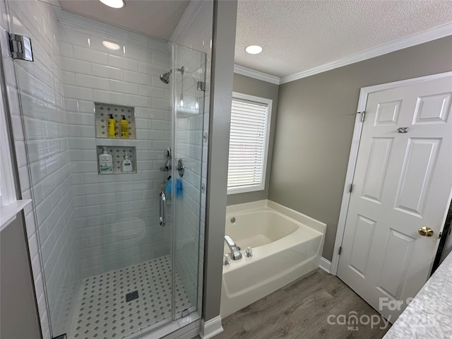 bathroom with plus walk in shower, hardwood / wood-style floors, a textured ceiling, and crown molding