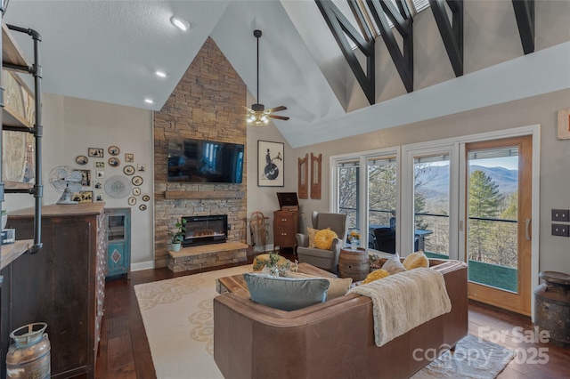 living room featuring high vaulted ceiling, ceiling fan, dark wood-type flooring, and a stone fireplace