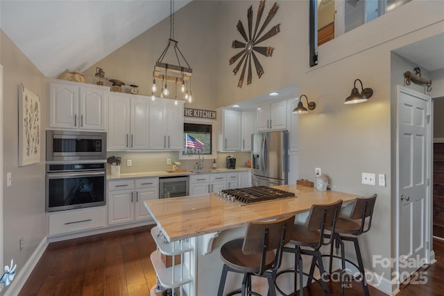 kitchen with white cabinets, a kitchen breakfast bar, appliances with stainless steel finishes, tasteful backsplash, and kitchen peninsula