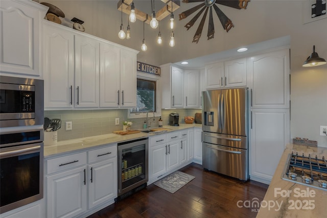 kitchen with white cabinets, pendant lighting, beverage cooler, and stainless steel appliances