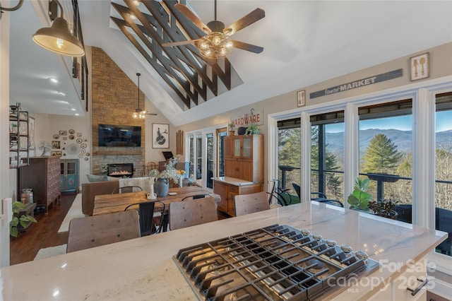 kitchen with ceiling fan, dark wood-type flooring, pendant lighting, high vaulted ceiling, and a fireplace