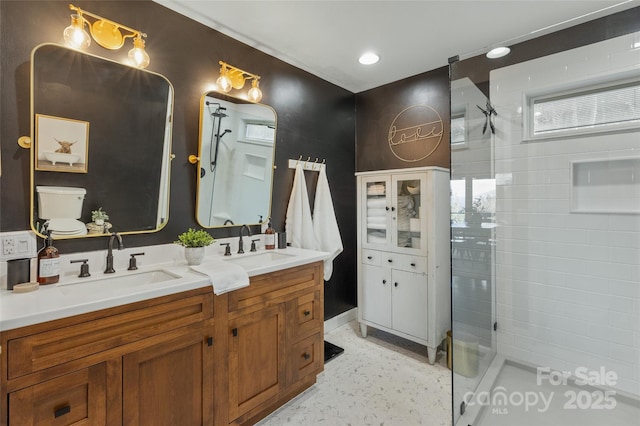 bathroom with tiled shower, vanity, and toilet