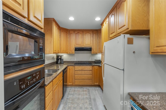 kitchen with black appliances, dark stone counters, and light hardwood / wood-style flooring