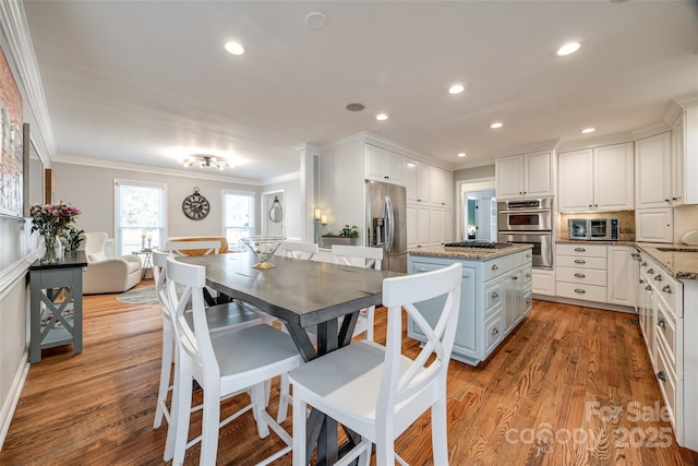 kitchen featuring stainless steel appliances, white cabinetry, light wood-type flooring, tasteful backsplash, and stone countertops