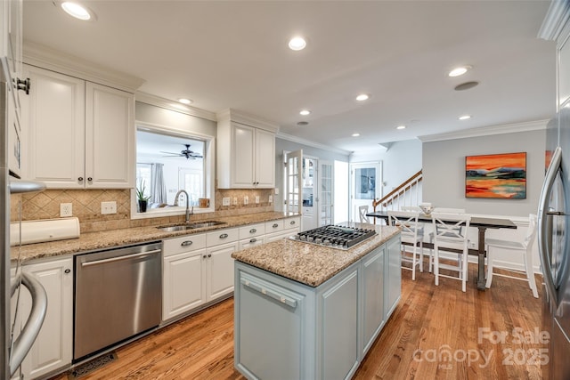 kitchen with sink, a center island, white cabinetry, light stone countertops, and appliances with stainless steel finishes