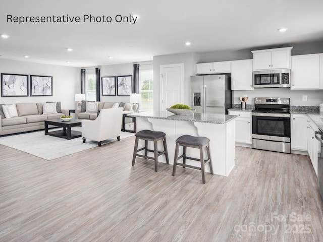 kitchen with white cabinetry, appliances with stainless steel finishes, a kitchen island, and a breakfast bar area