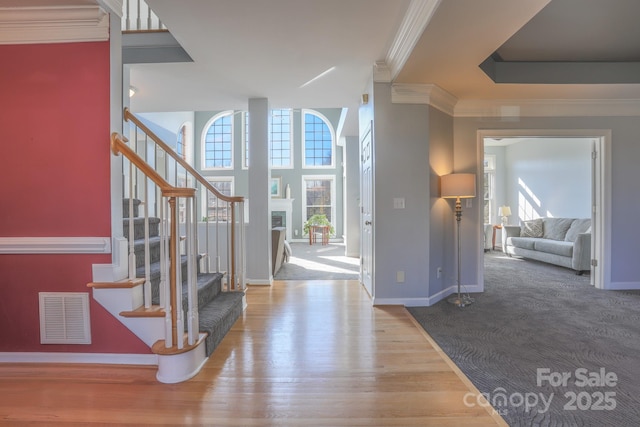 entrance foyer with ornamental molding and hardwood / wood-style floors