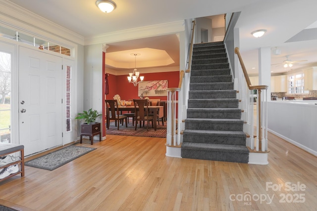 entrance foyer featuring crown molding, a notable chandelier, light hardwood / wood-style floors, and a tray ceiling