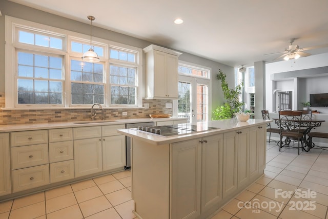 kitchen featuring a kitchen island, decorative light fixtures, sink, decorative backsplash, and black electric cooktop