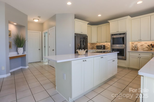 kitchen with light tile patterned floors, decorative backsplash, black appliances, and a kitchen island