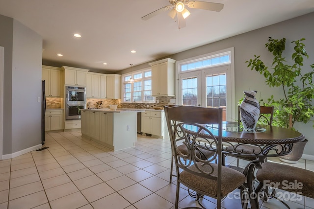 kitchen featuring black fridge, tasteful backsplash, light tile patterned floors, double oven, and a kitchen island