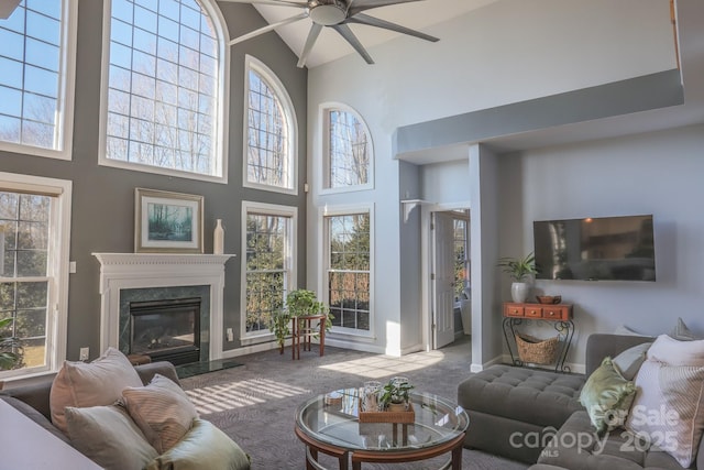 living room with ceiling fan, a premium fireplace, carpet floors, and a high ceiling