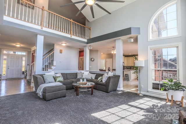 living room with ceiling fan, carpet floors, and a high ceiling