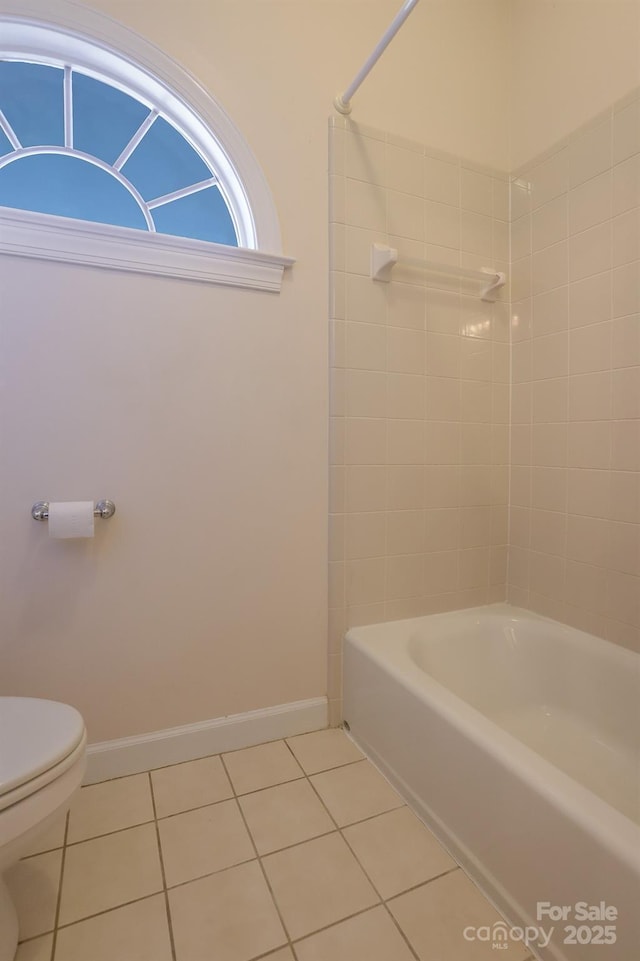 bathroom with tile patterned flooring, tiled shower / bath combo, and toilet