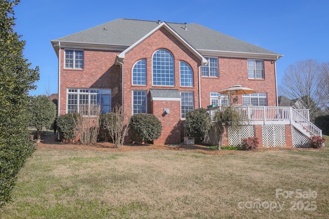 back of property with a wooden deck and a lawn