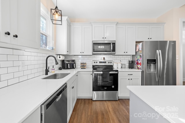 kitchen with appliances with stainless steel finishes, pendant lighting, white cabinetry, and sink