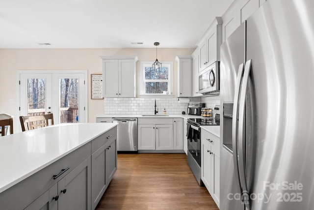 kitchen featuring stainless steel appliances, backsplash, decorative light fixtures, french doors, and sink