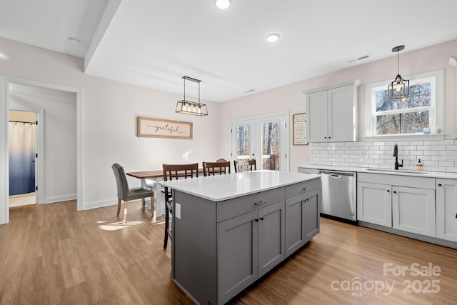 kitchen with dishwasher, a kitchen island, sink, hanging light fixtures, and gray cabinets