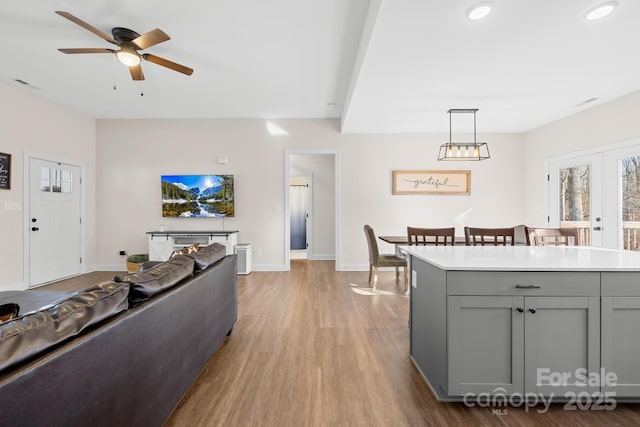 interior space with ceiling fan, gray cabinetry, french doors, and hanging light fixtures