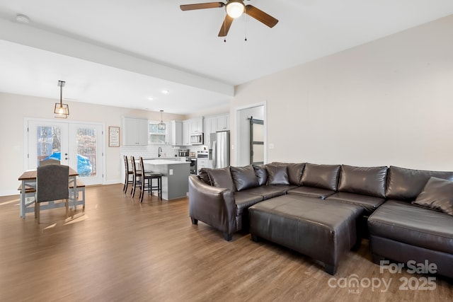 living room featuring ceiling fan, french doors, and light wood-type flooring