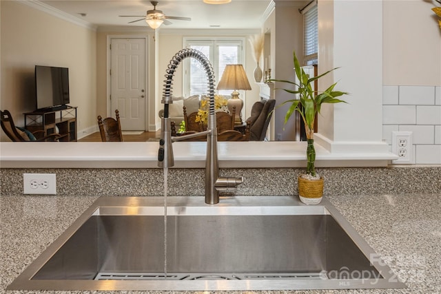 interior details featuring ceiling fan, sink, ornamental molding, and tasteful backsplash