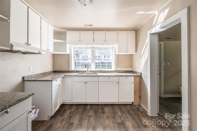 kitchen with dark hardwood / wood-style floors, white cabinetry, sink, and dark stone counters