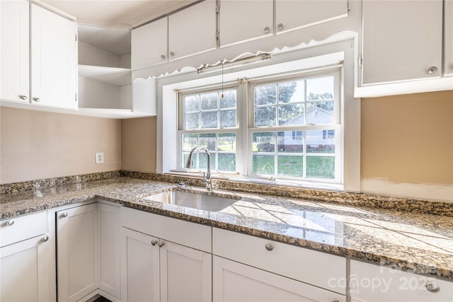 kitchen featuring white cabinetry, dark stone countertops, and sink