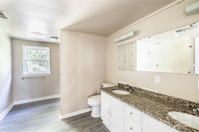 bathroom with wood walls, toilet, vanity, and hardwood / wood-style flooring